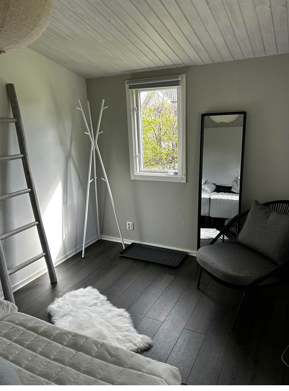 Innenraum mit Holzleiter, Kleiderständer, Standspiegel und Schaffell auf dunklem Boden.