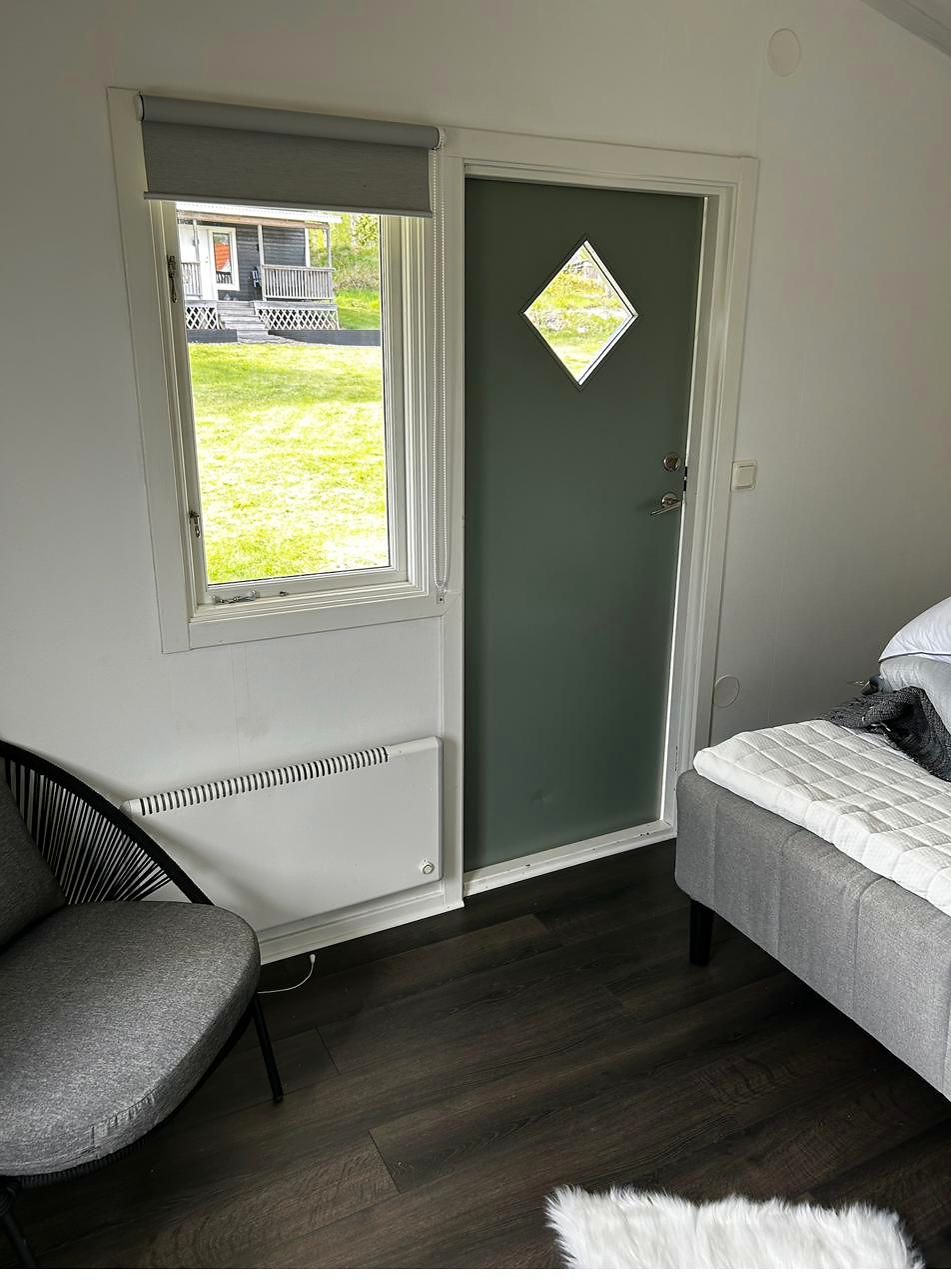 Grüne Tür mit Rautenfenster von innen, daneben ein Fenster mit Blick auf die Wiese.
