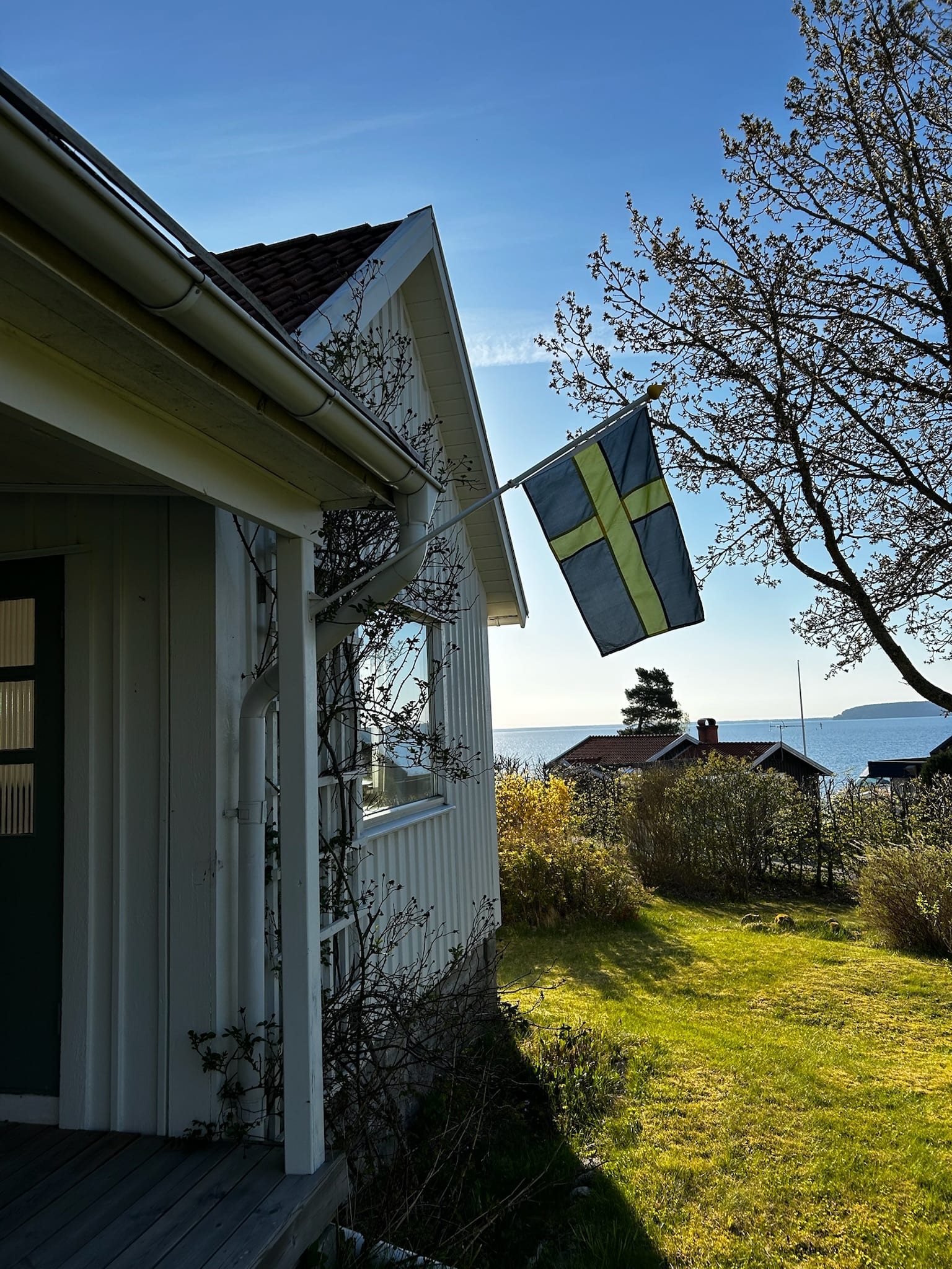 Blick am Giebel des Haupthauses entlang zur schwedischen Flagge, im Hintergrund der Vänernsee.
